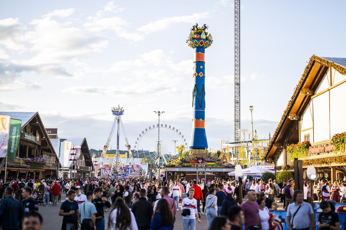 Die Fruchtsäule thront über dem Wasen. Zahlreiche Besuchende laufen daran vorbei und schlendern über den Platz.