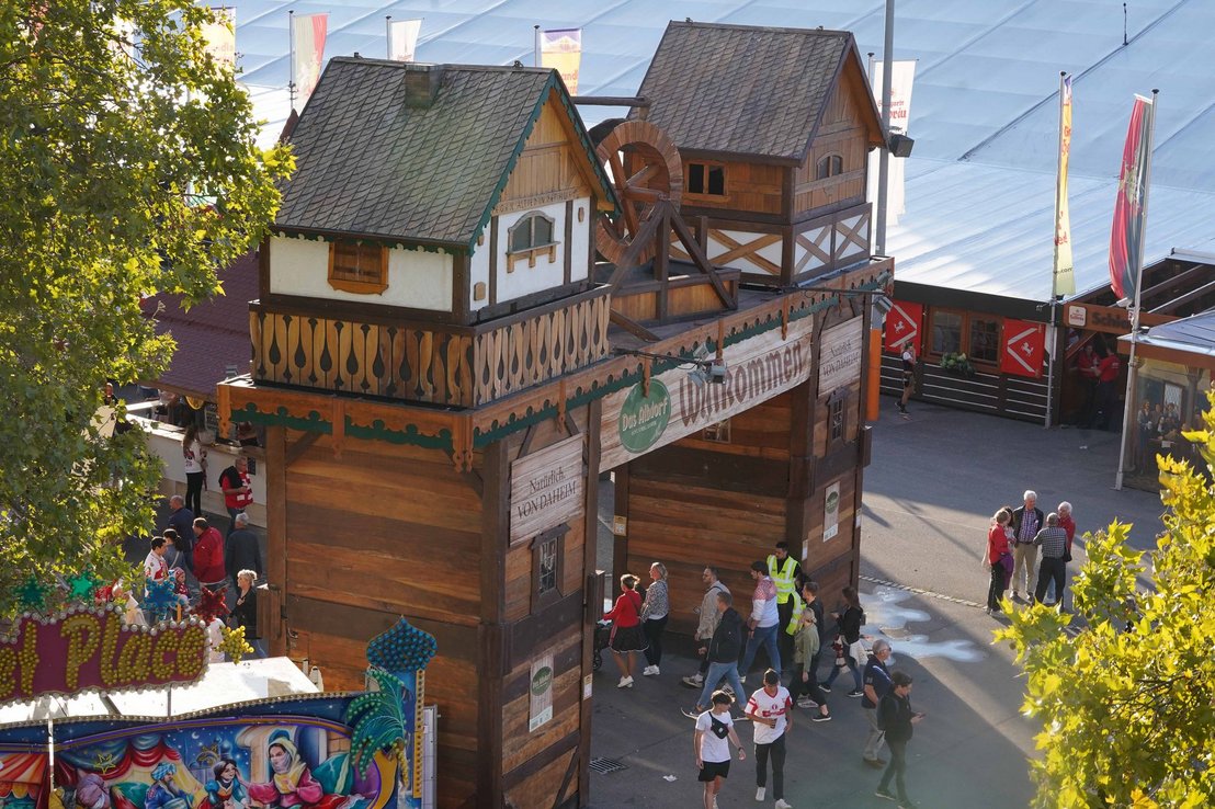 Das Holz-Eingangstor des Albdorfs mit einem großen Banner auf dem "Willkommen" steht.