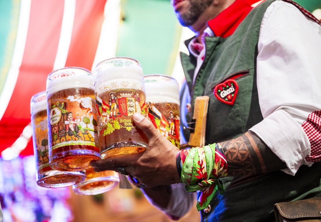 Festzelt-Kellner trägt mehrere Maß Bier