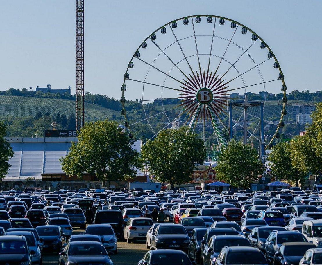 großer Parkplatz mit Autos darauf, im Hintergrund Riesenrad