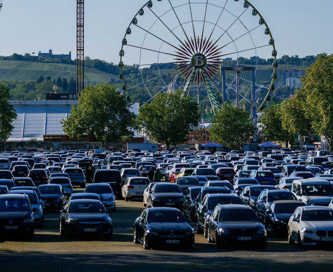 [Translate to English:] großer Parkplatz mit Autos darauf, im Hintergrund Riesenrad